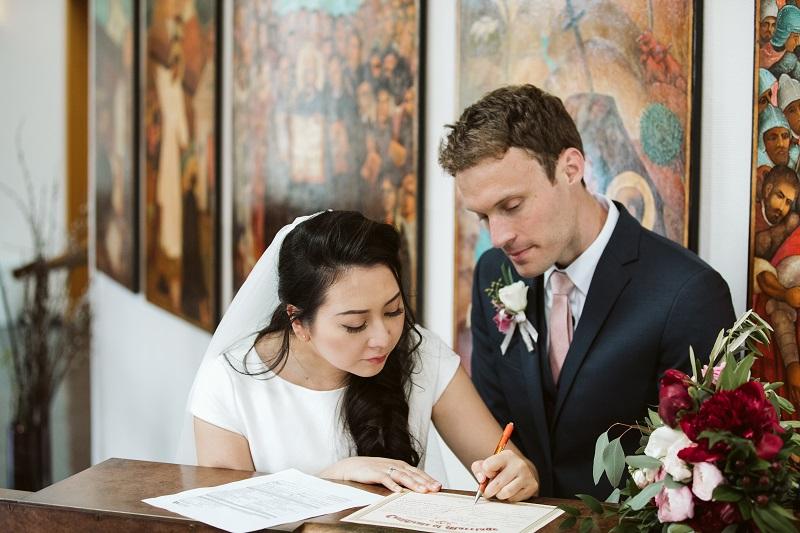 a newlywed couple signs their marriage license in front of the Chapel icons of St. 伊格内修斯