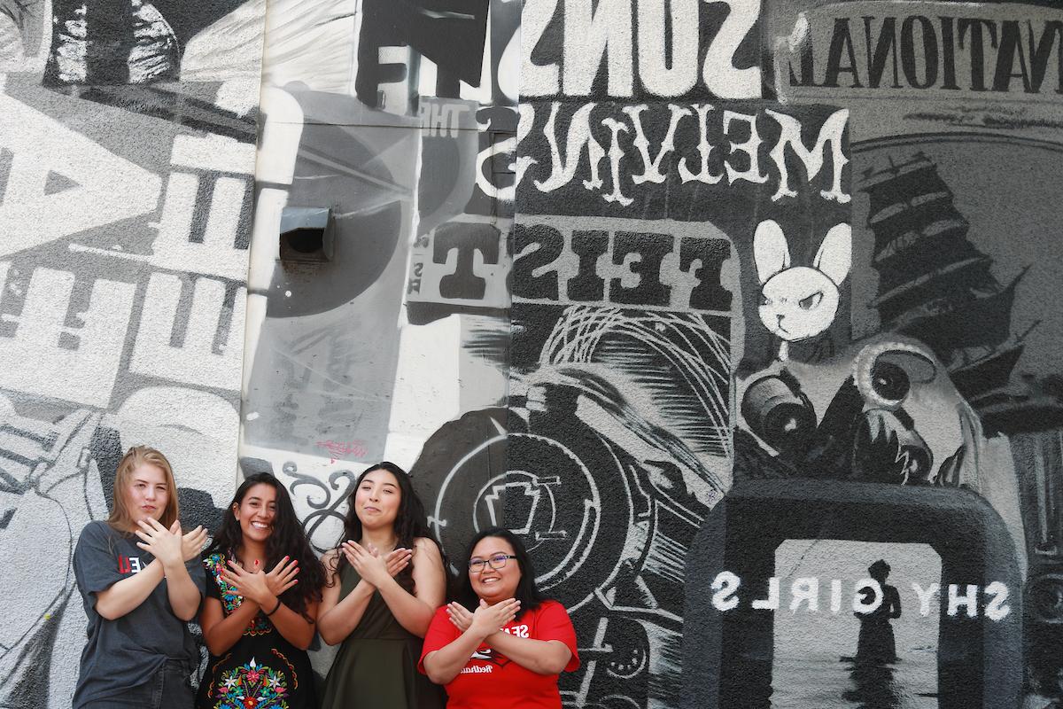 四个BG大游的学生站在纽莫夜总会外的音乐主题壁画前